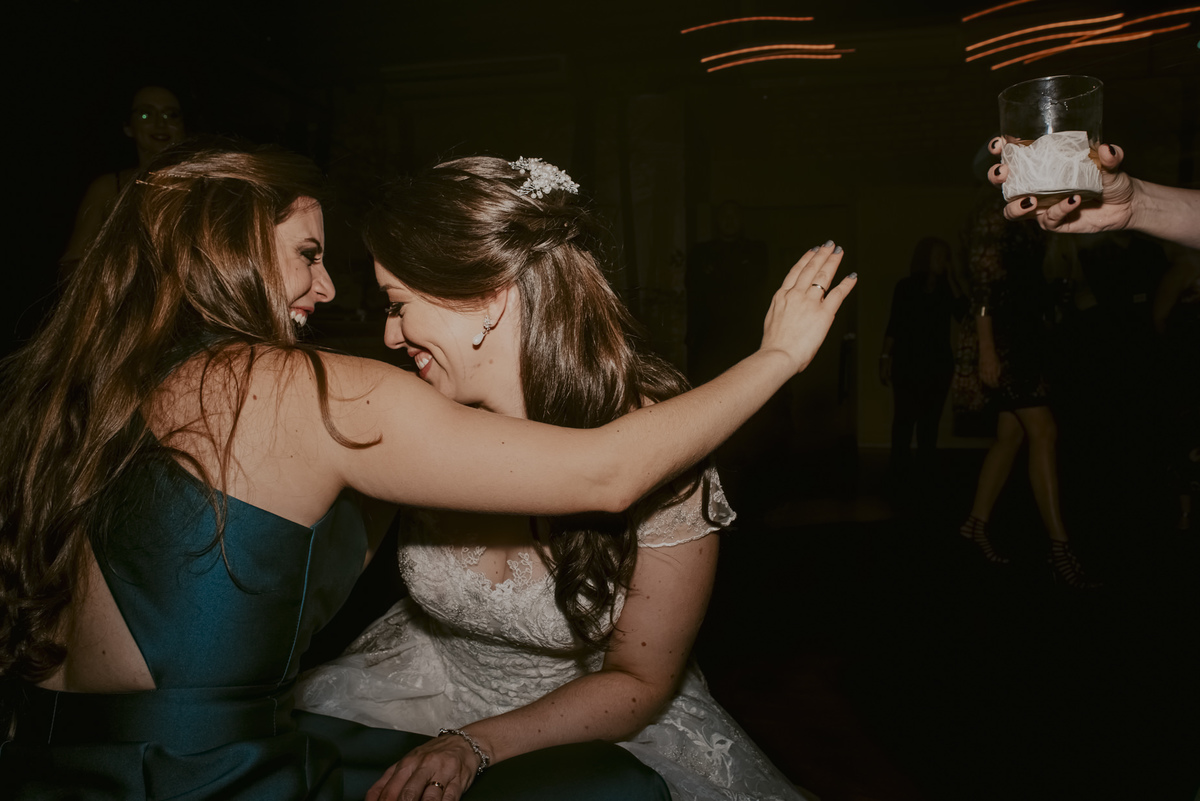 a noiva dançando com sua amiga com um copo de bebida estão animadas fotografia de casamento unica fotografo de casamento sp