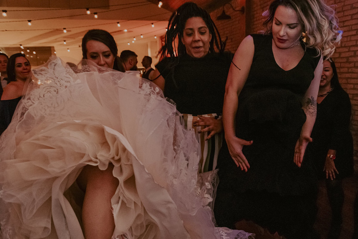 a noiva levantou o vestido de noiva para conversar com as amigas pertinho do final da festa de casamento