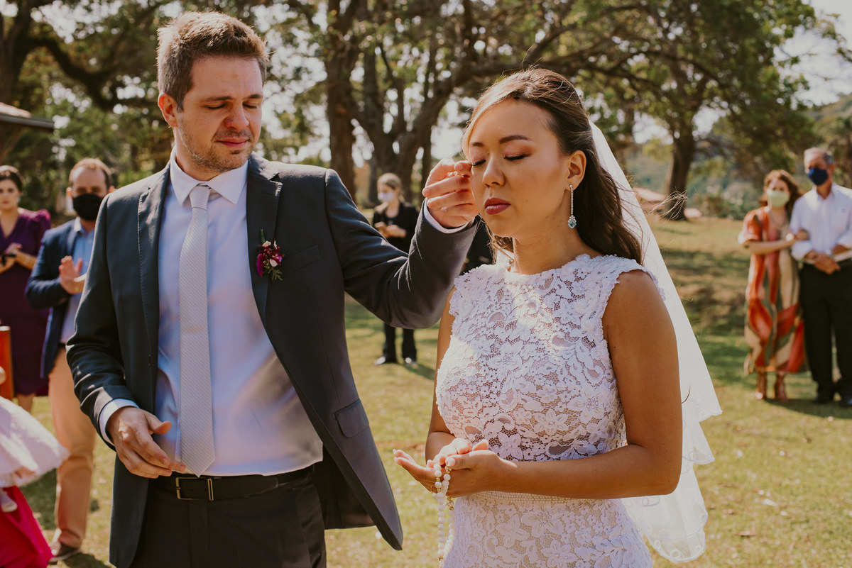p noivo faz carinho na noiva durante a celebraçnao da cerimonia 