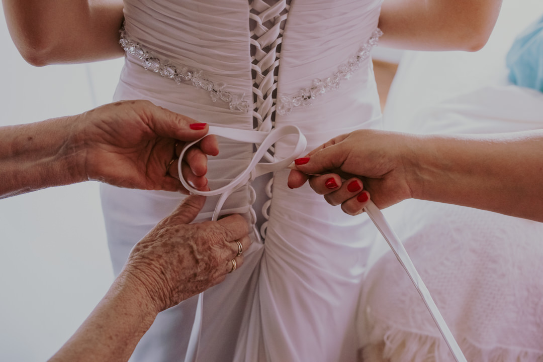 o vestido da noiva sendo abotoado pelas madrinha foto de casamento daniel okuyama fotografia 