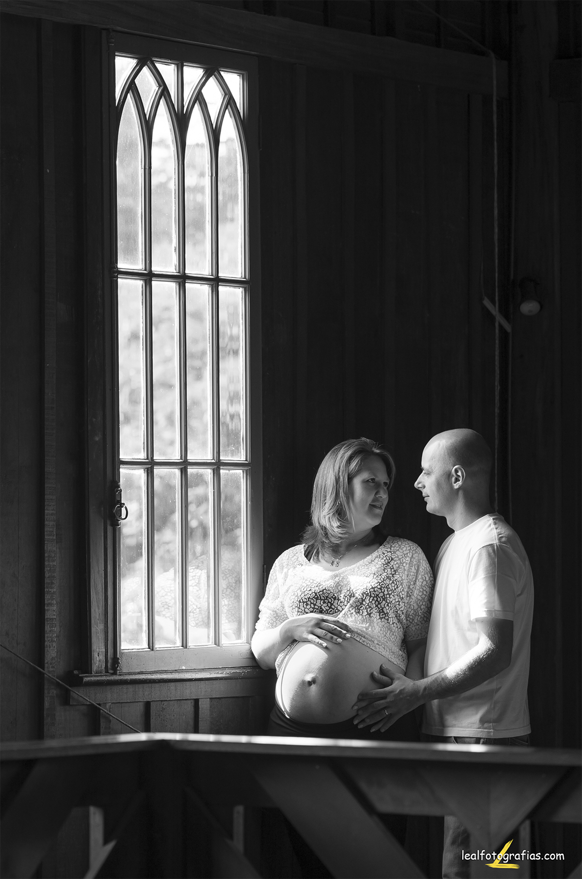 foto em preto e branco de casal na janela com luz natural