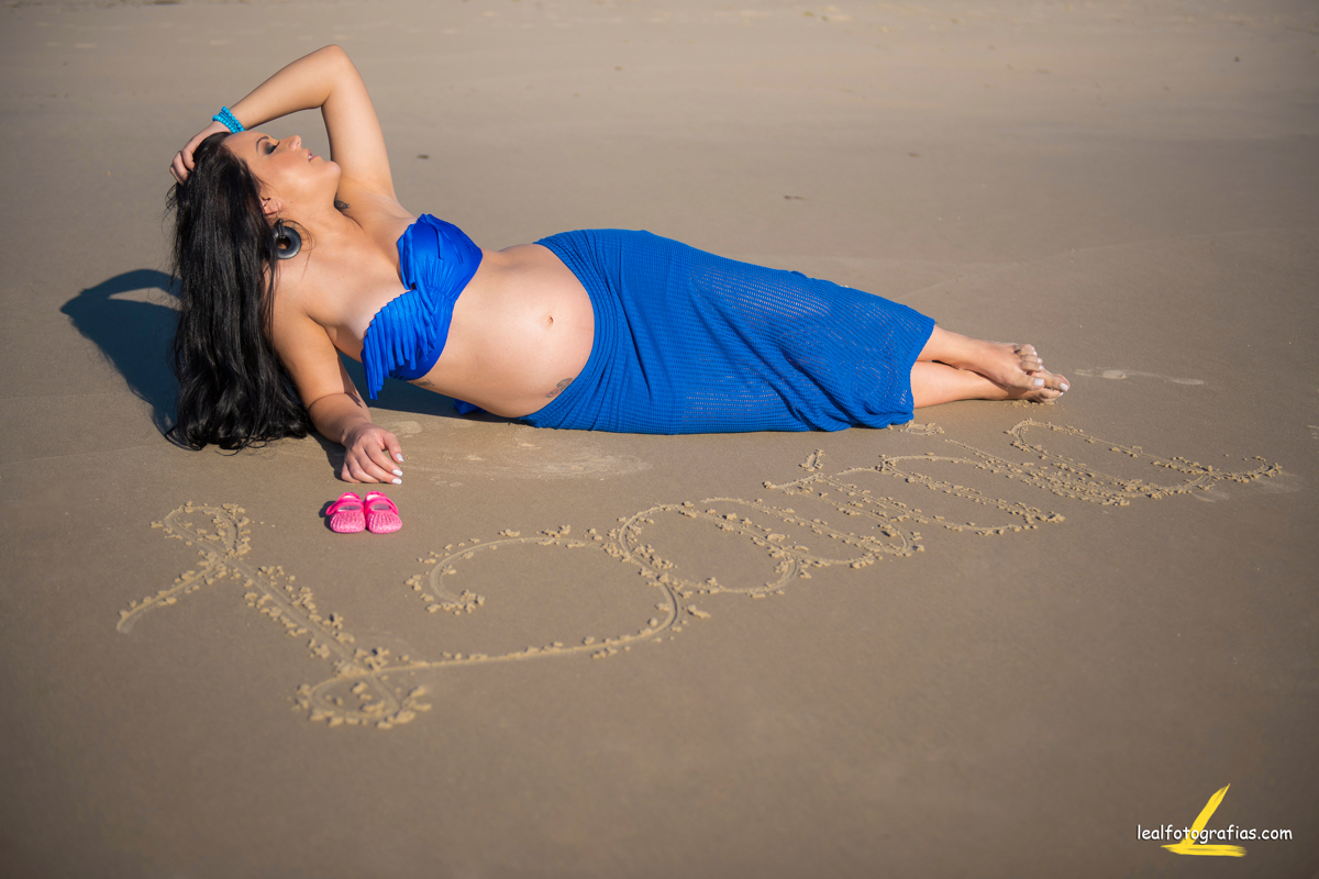 mamãe deitada na areia com o nome da filha escrito