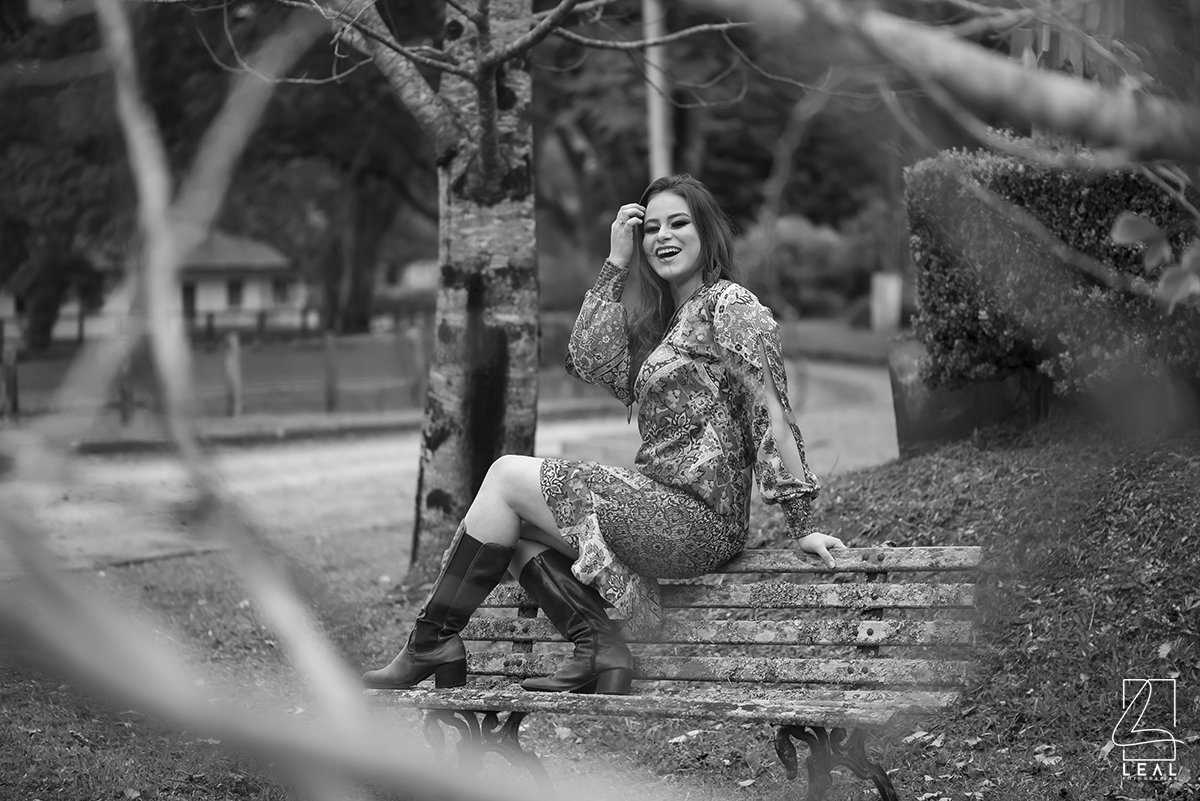 Mulher sentada no banco de praça em ensaio fotográfico preto e branco