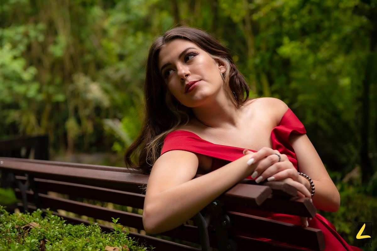 Menina de vestido vermelho sentada em banco no bosque do alemão