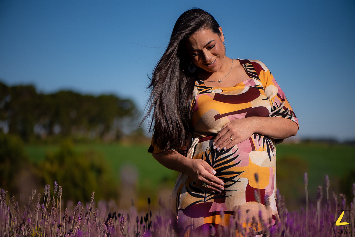 Linda foto de gestante segurando a barriga em plantação de lavandas por Leal Fotografias