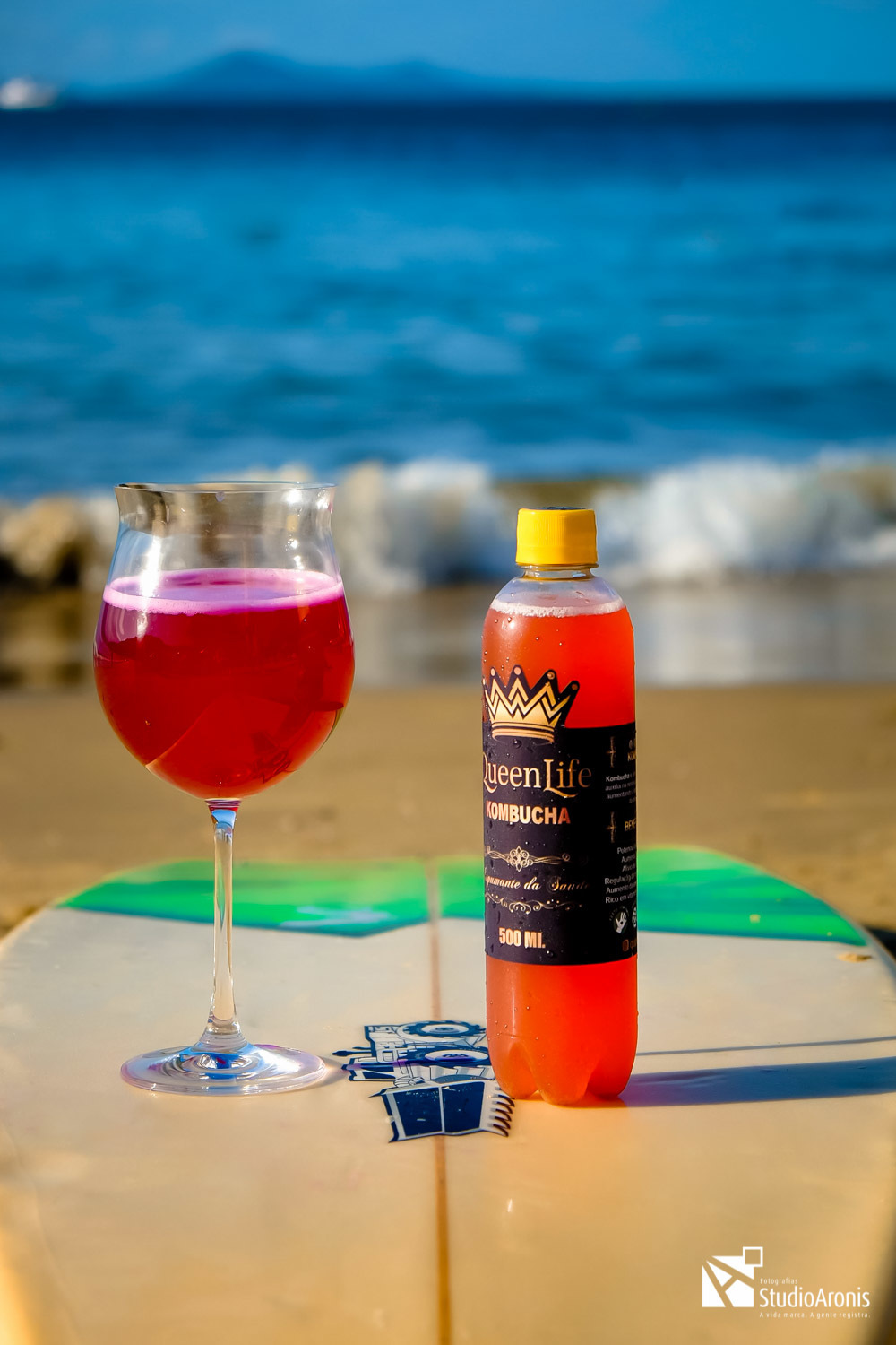 Fotografia de Produtos - Kombuchas - Espumante da Saúde - Balneário Camboriú - Santa Catarina - Prancha de Surf - praia - mar - foto conceito - areia - taça - espumante - fotos com estilo