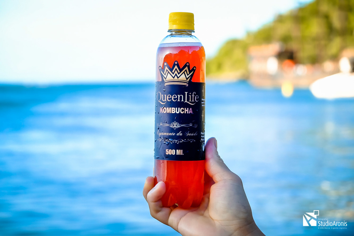segurando uma garrafa de kombucha praia de larajeiras balneario camboriu santa catarina - fotos de produtos criativas - studio aronis fotografias - mar