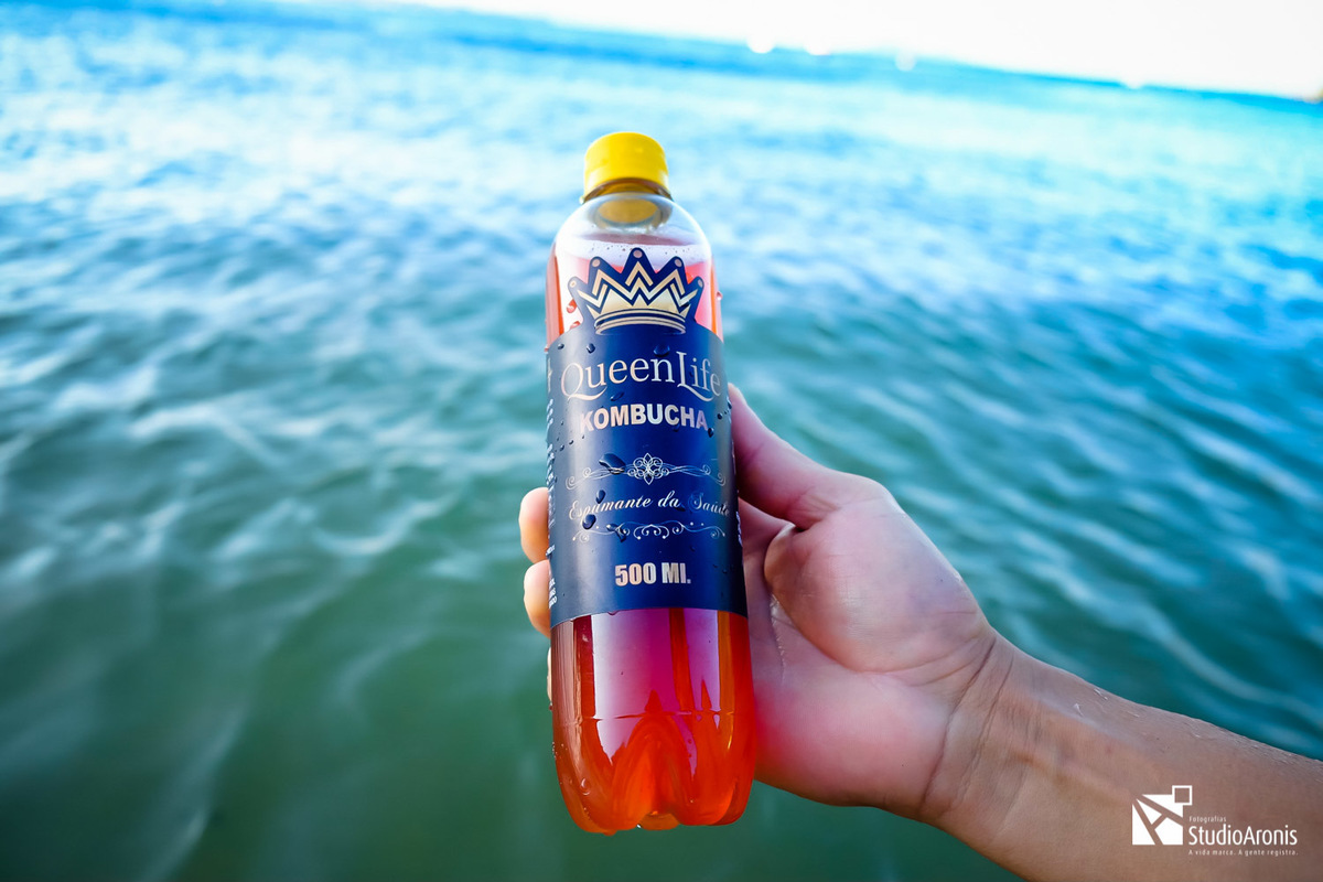 segurando uma garrafa de kombucha praia de larajeiras balneario camboriu santa catarina - fotos de produtos criativas - studio aronis fotografias - mar