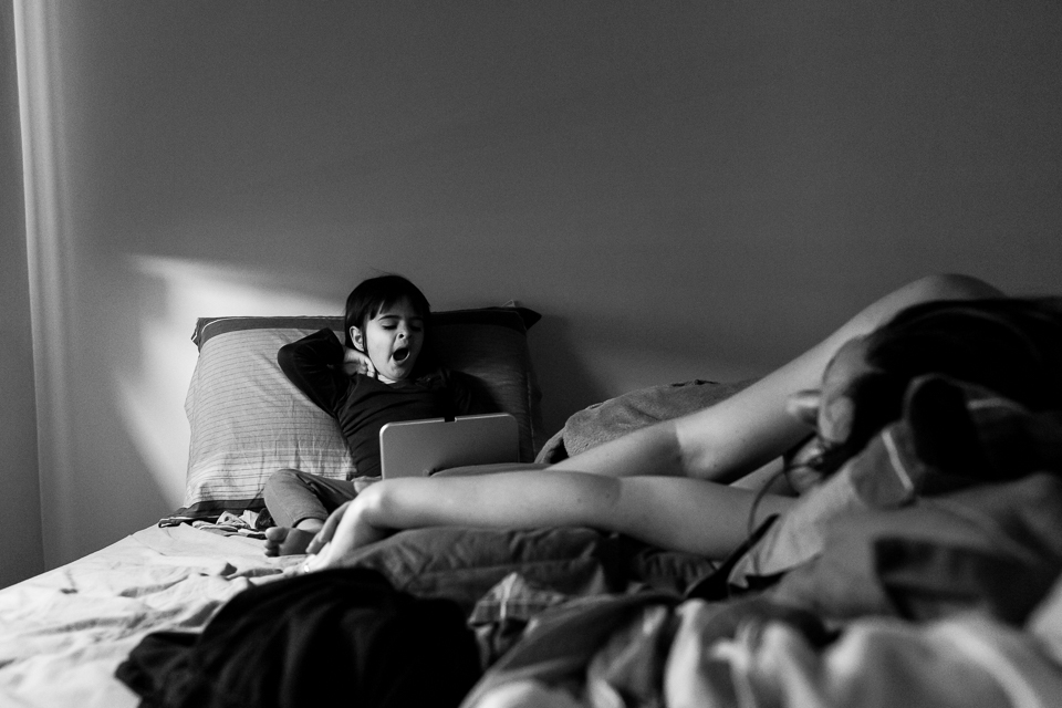 mãe gestante deitada repousando com quase 40 semanas de gestação e filha na cama no tablet