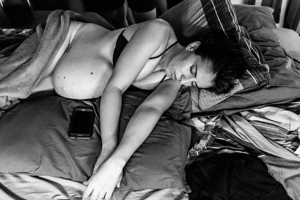 gestante deitada na sua cama ouvindo música no celular para aliviar as contrações 