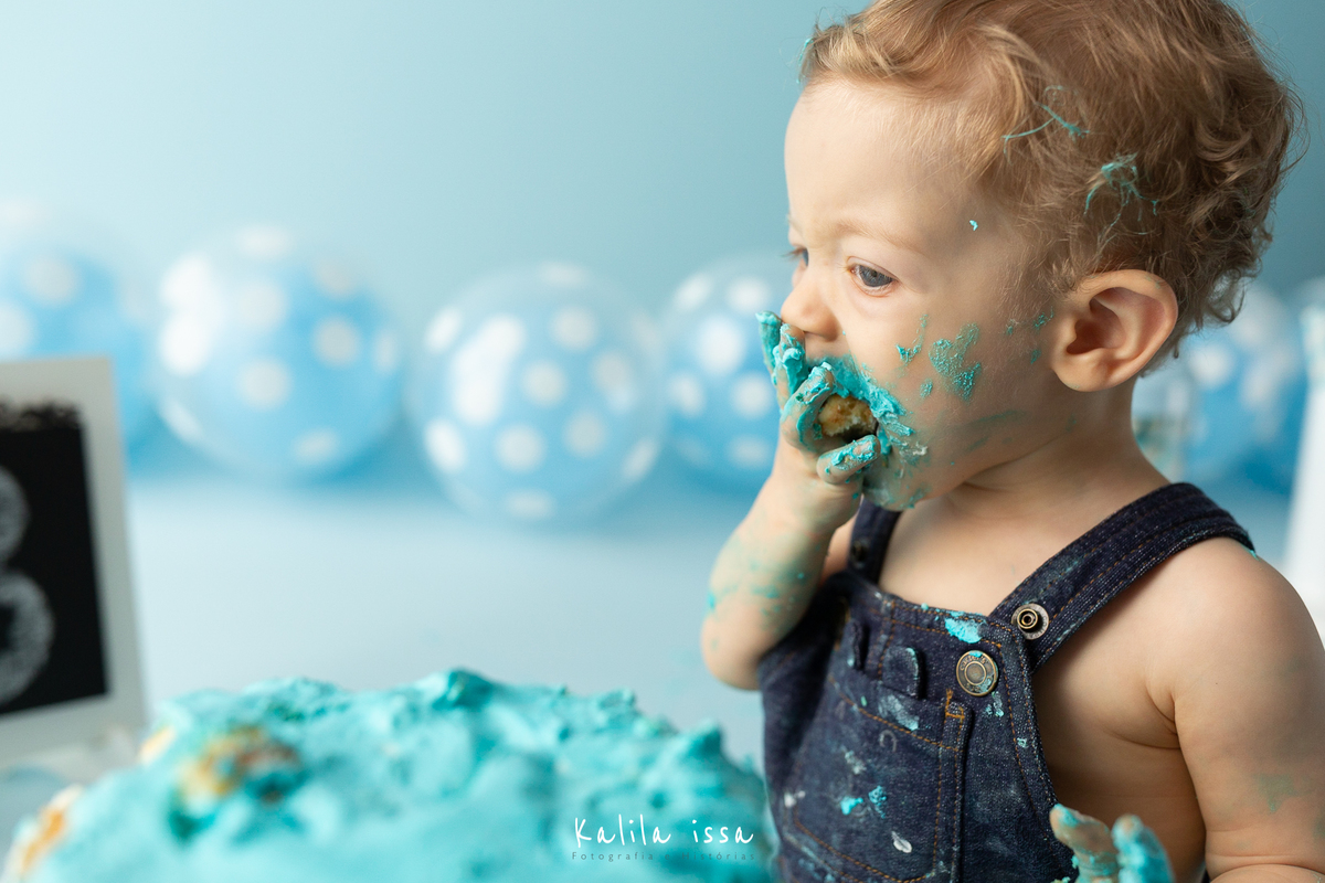 criança come o bolo do smash the cake com muita vontade 