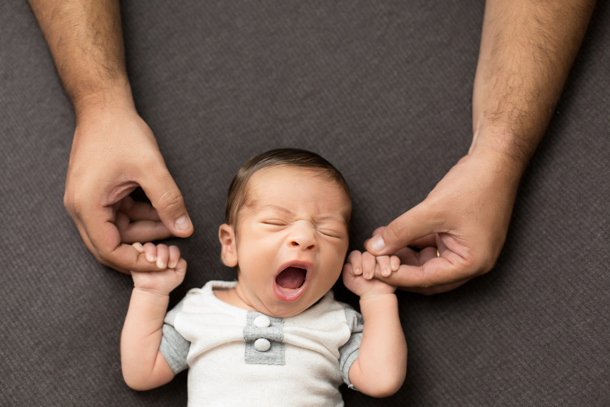 newborn bocejando nos bracos do papai