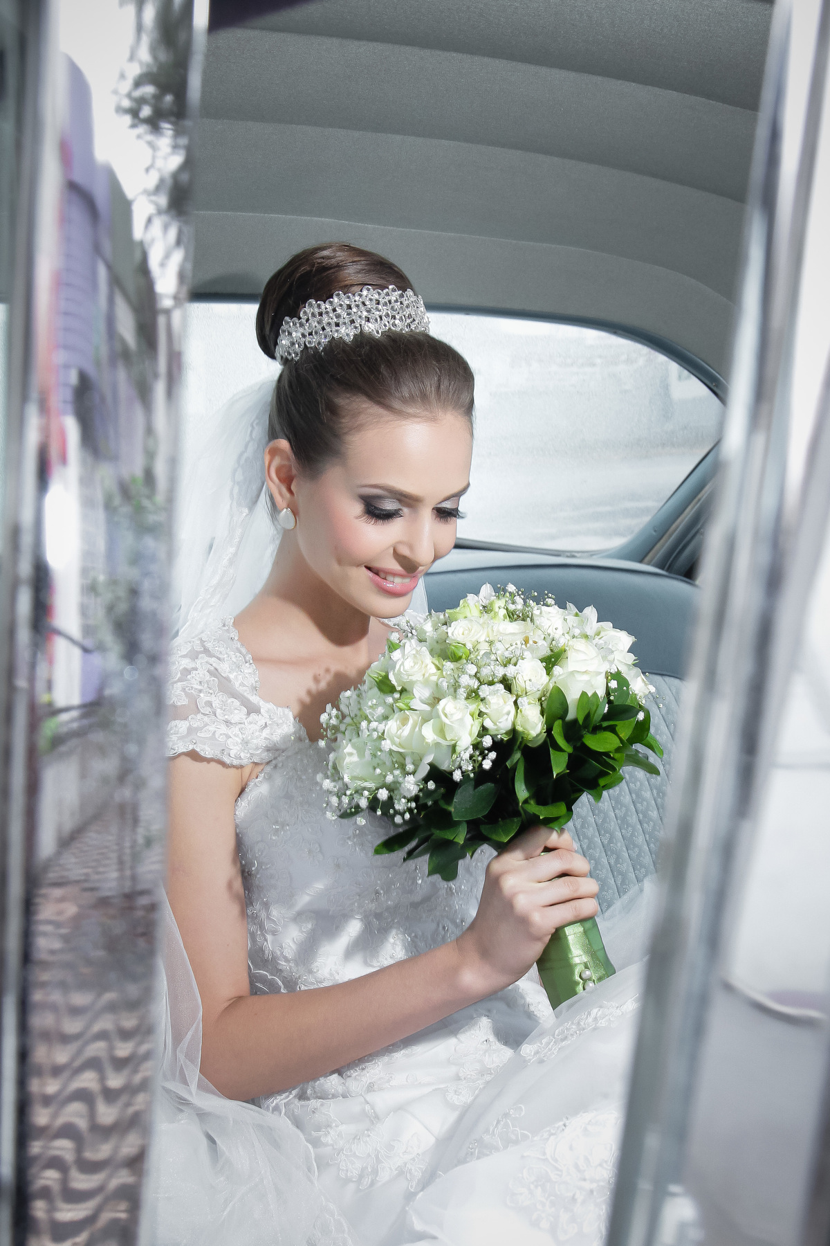 Noiva no carro cadillac  olhando buquê de flores
