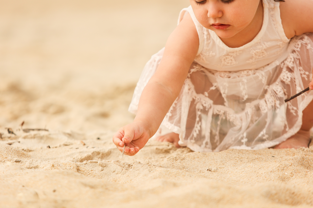 criança brincando com a areia na praia, 
