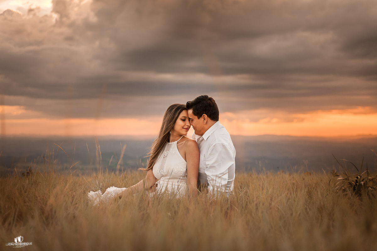 CASAL SENTADO NO TODO DO MUNDO COM POR DO SOL