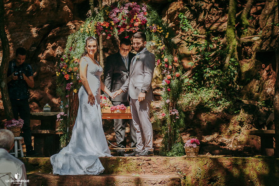 NOIVOS DE MÃOS DADAS OLHANDO A DAMINHA ENTRAR COM AS ALIANÇAS