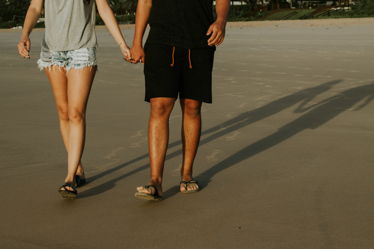 Casal de mãos dadas caminhando na praia