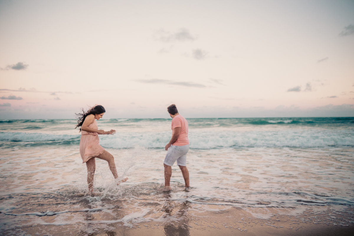 Casal chutando água na praia