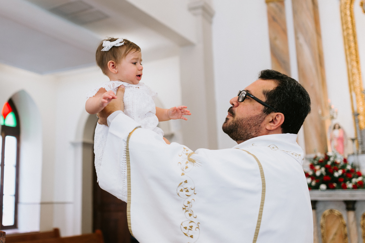 bebê sendo levantado pelo padre