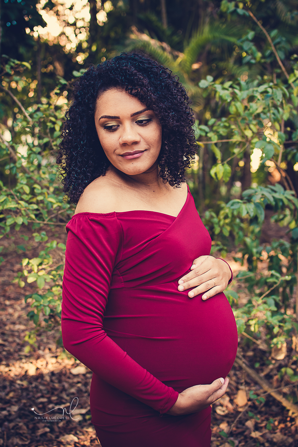 uma linda gestante que foi fotografada pela fotografa nailie lucchesi, no estudio amora, ela veste um lindo vestido longo e vermelho