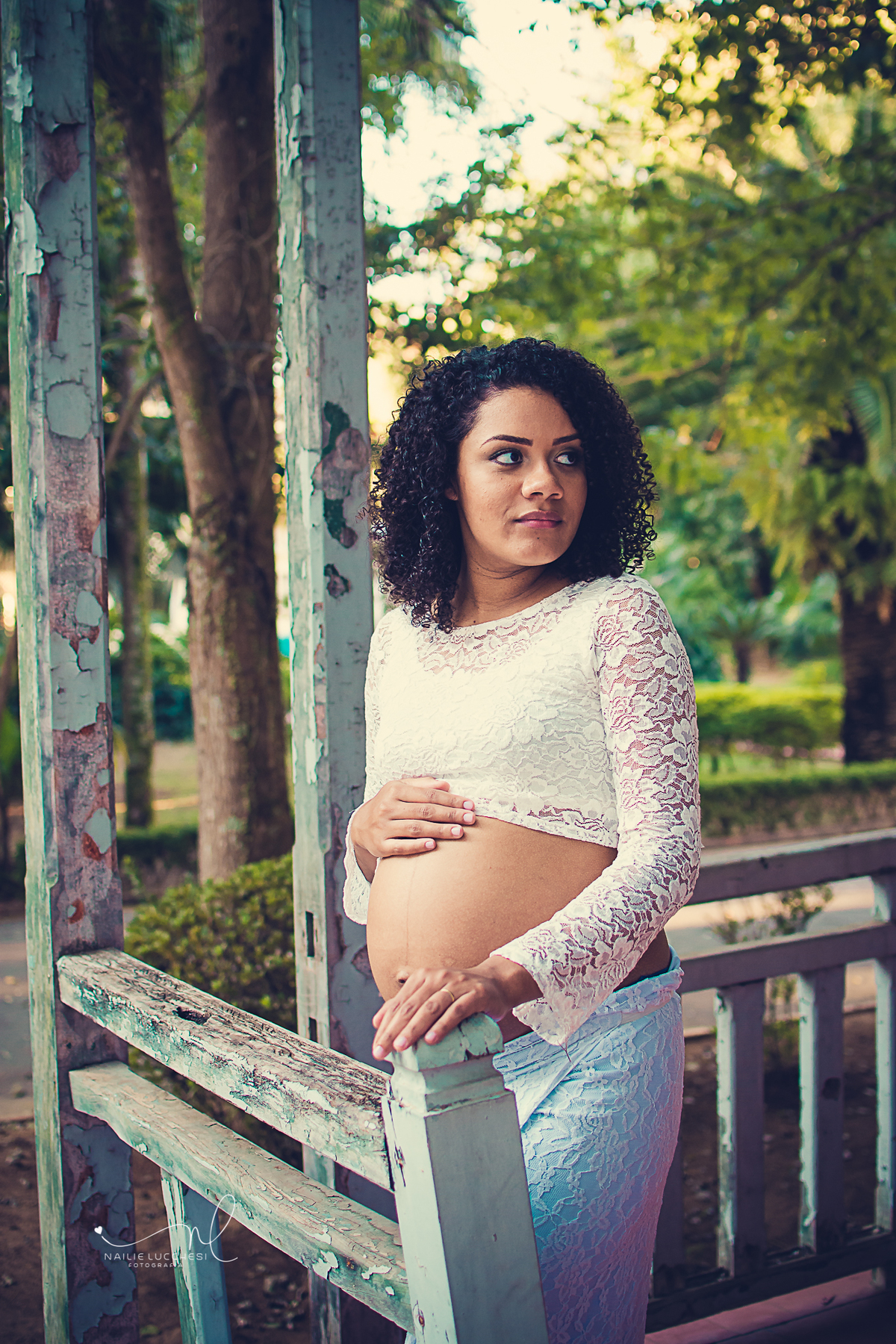 gestante de pele negra, vestido branco e mostrando a sua barriga, fotografada por nailie lucchesi no estudio amora,