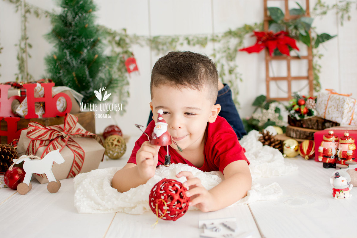 esse é o caio, esta brincando no cenário de natal do estúdio nailie lucchesi, esta brincando com um papai noel