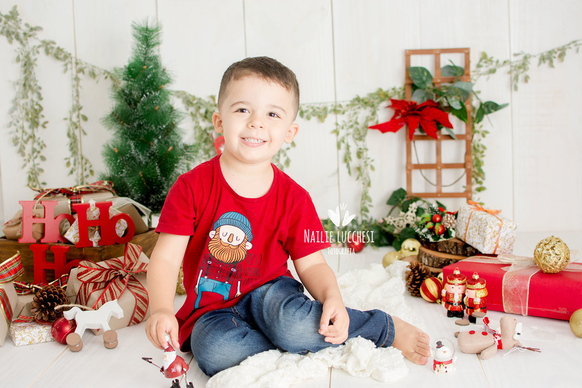 caio 3 anos, brincando com presentes de natal, esta de camisa vermelha no estudio nailie lucchesi