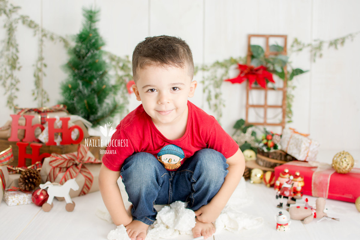 caio 3 anos de vermelho esta agachado, e sorrindo