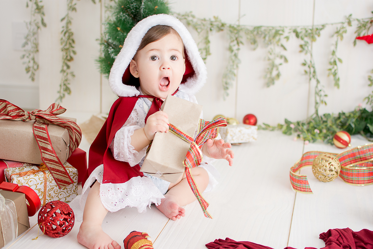 uma menina linda e vestida de vermelho, brincando no ensaio de natal no estudio da nailie lucchesi