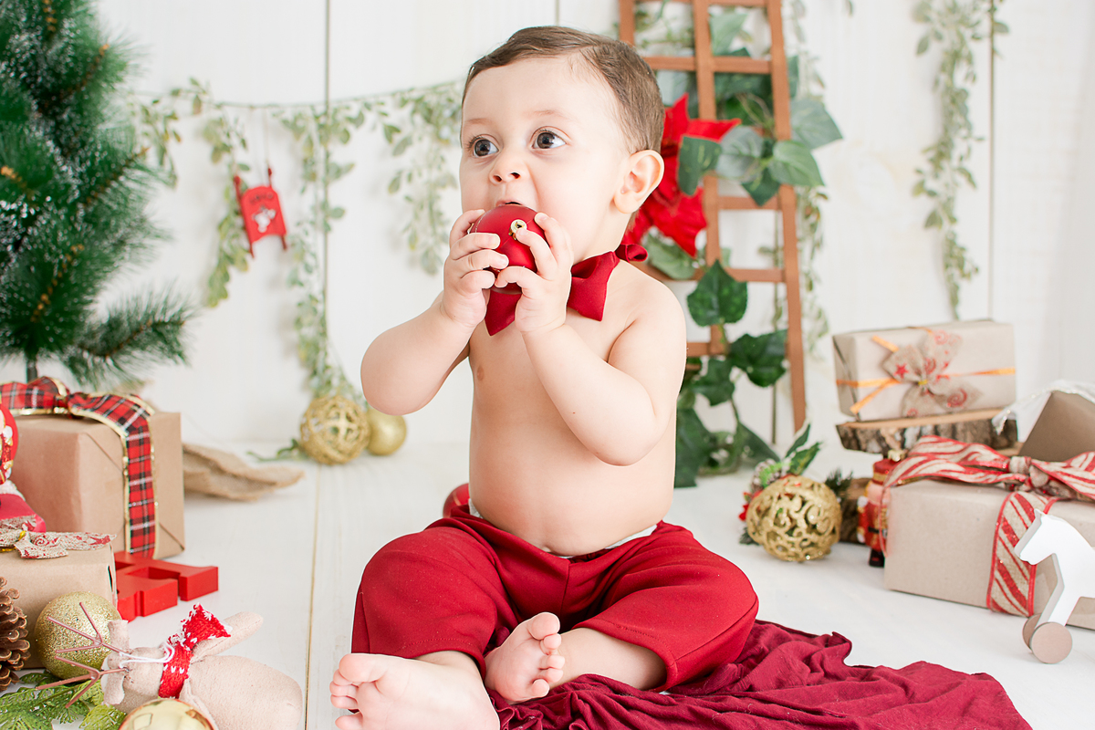 um bebe brincando no cenario de natal do estudio amora e foi fotografado por nailie lucchesi
