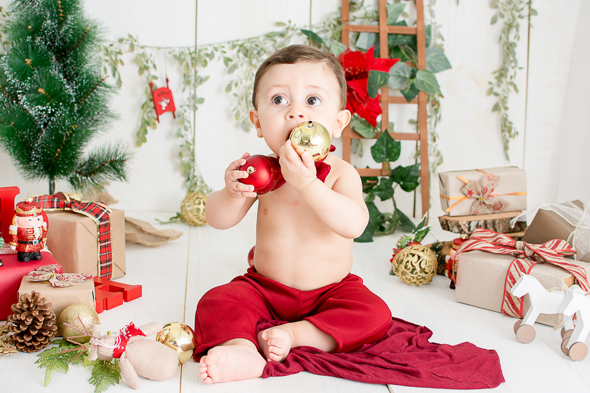 um bebe brincando no cenario de natal do estudio amora e foi fotografado por nailie lucchesi