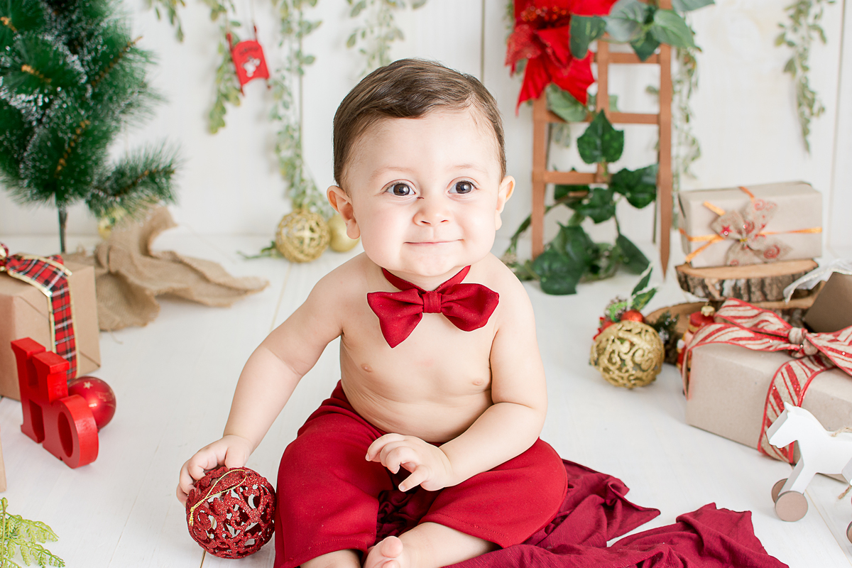 um bebe brincando no cenario de natal do estudio amora e foi fotografado por nailie lucchesi