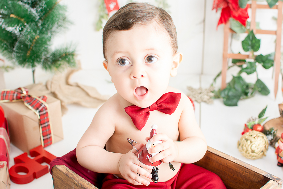 um bebe brincando no cenario de natal do estudio amora e foi fotografado por nailie lucchesi
