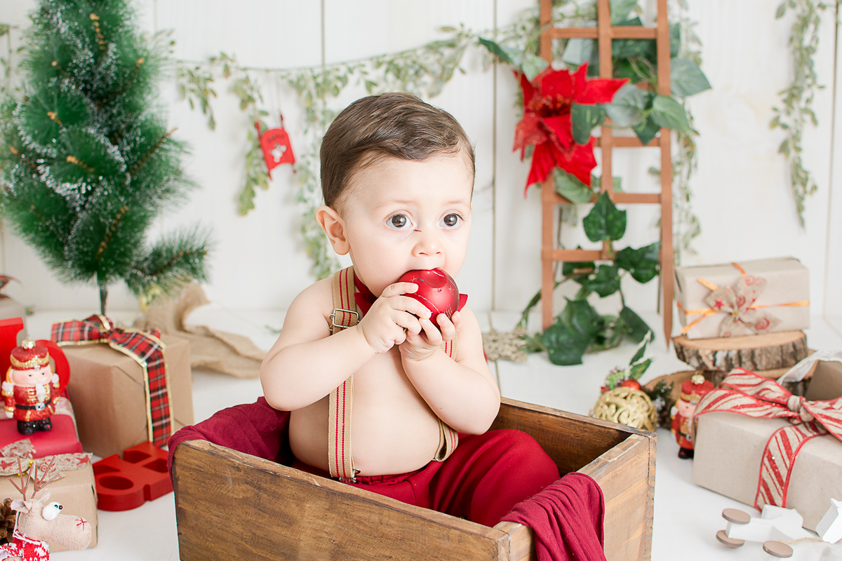 um bebe brincando no cenario de natal do estudio amora e foi fotografado por nailie lucchesi