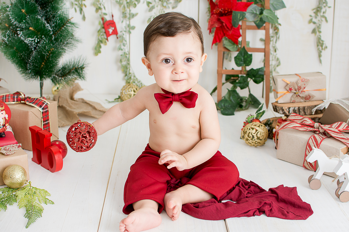 um bebe brincando no cenario de natal do estudio amora e foi fotografado por nailie lucchesi