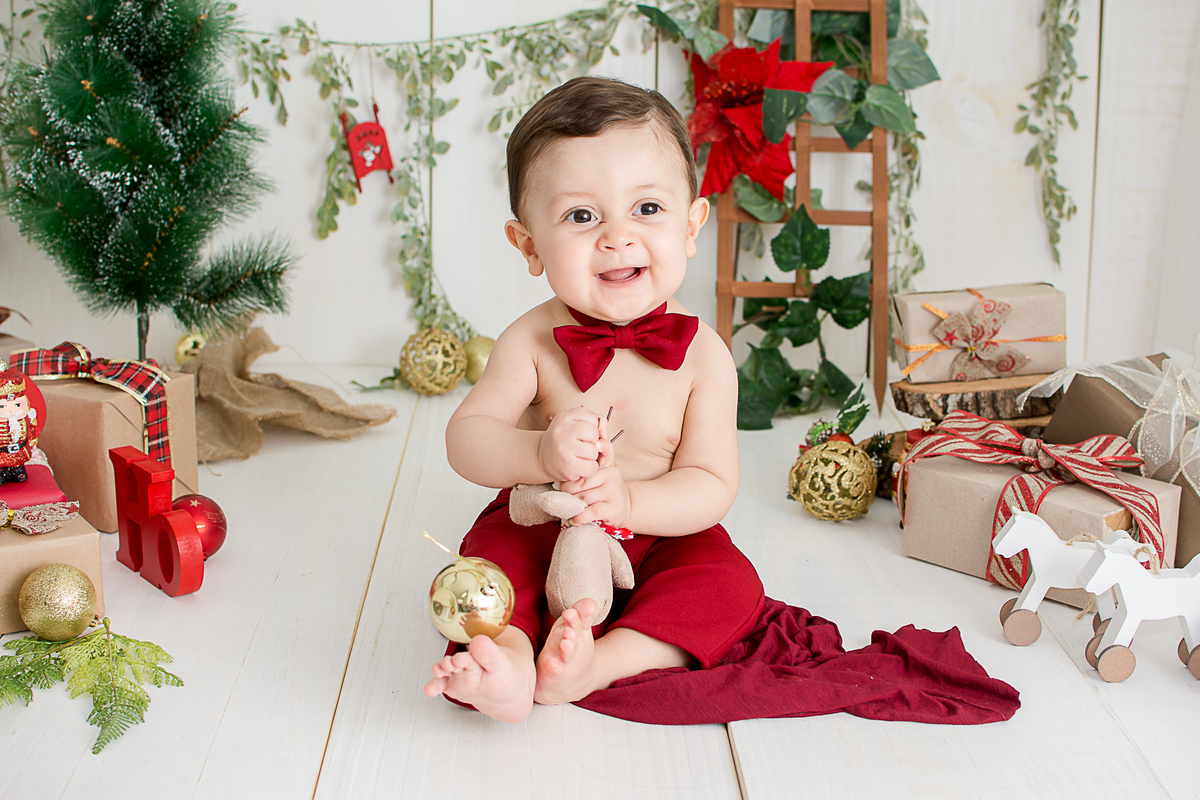 um bebe brincando no cenario de natal do estudio amora e foi fotografado por nailie lucchesi