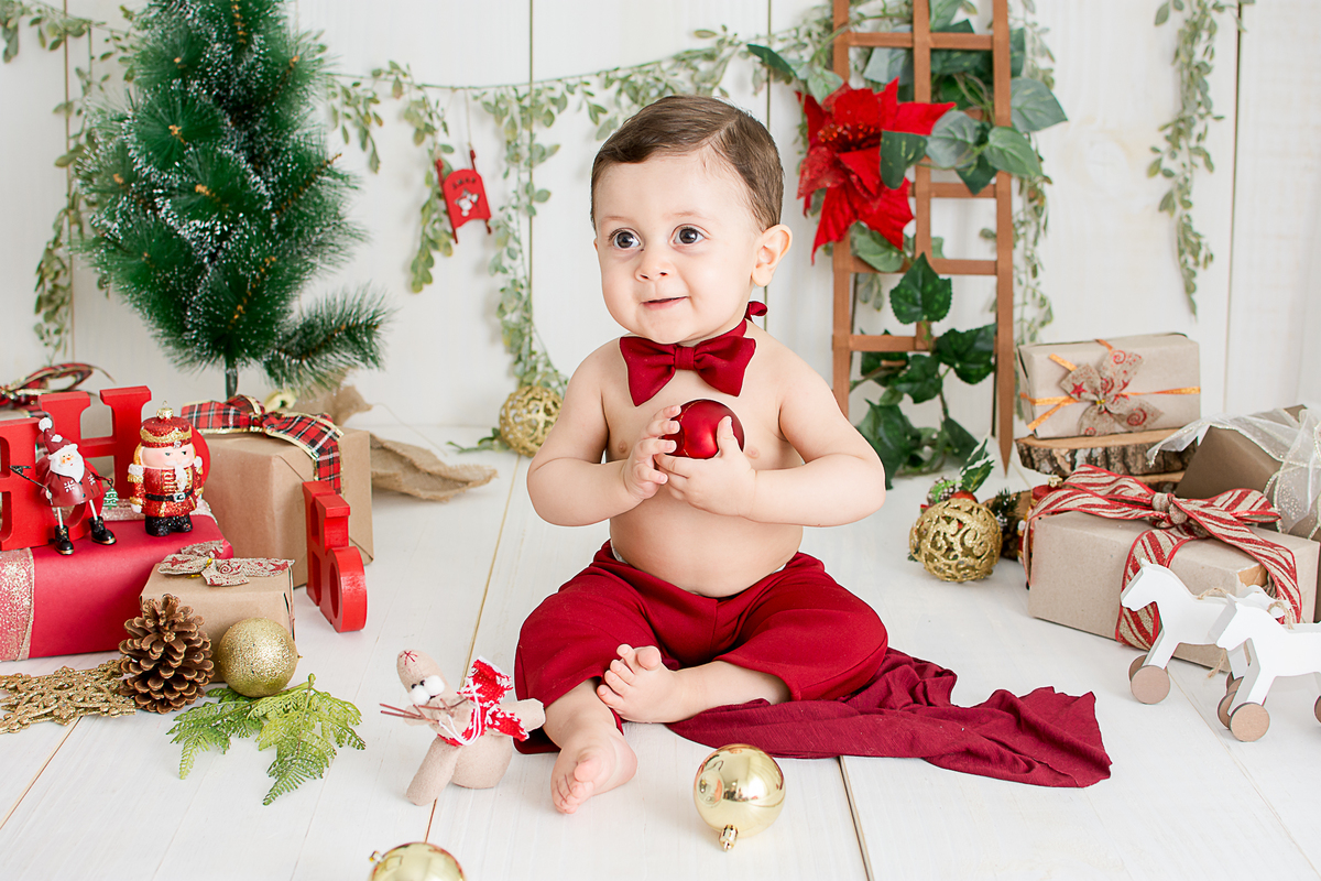 um bebe brincando no cenario de natal do estudio amora e foi fotografado por nailie lucchesi