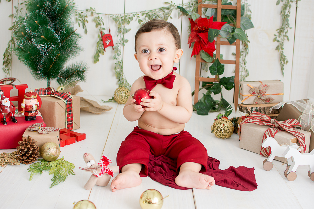 um bebe brincando no cenario de natal do estudio amora e foi fotografado por nailie lucchesi