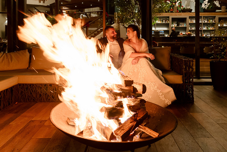 Chico e Cacau relaxam em frente à lareira externa no Bendito Cacao. O fogo aquece a noite em Campos do Jordão, criando um clima sofisticado e aconchegante para este casamento íntimo na serra.