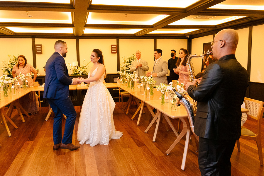 Chico e Cacau dançam animados ao som de um saxofonista ao vivo durante o jantar no Bendito Cacao. A apresentação musical intimista traz elegância e descontração para a recepção do casamento em Campos do Jordão.