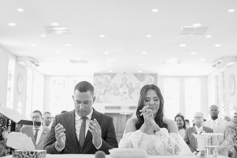 Momento de profunda conexão e fé. Em preto e branco, os noivos rezam emocionados no altar da Paróquia Espírito Santo, em São José dos Campos, antes do 