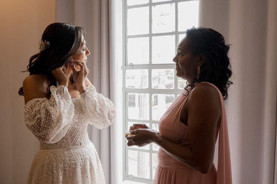 Amor de mãe não tem igual. A emoção e a ajuda materna nos últimos ajustes, colocando os brincos da noiva. Momentos de conexão familiar que tornam o making of inesquecível.