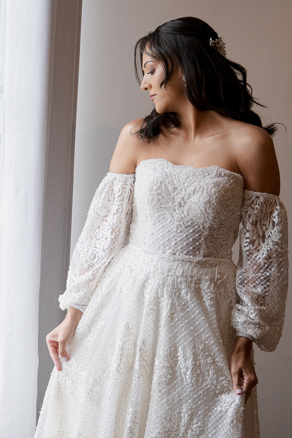 A sofisticação nos detalhes. Vestido de noiva com decote ombro a ombro e mangas bufantes em renda trabalhada. Inspiração de elegância romântica para noivas em São José dos Campos.