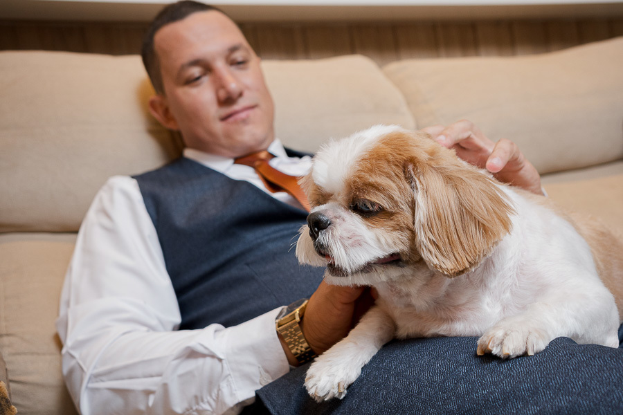 O melhor amigo também participa! Making of do noivo descontraído com o carinho do seu cachorro. Fotografia de casamento que valoriza cada membro da família.