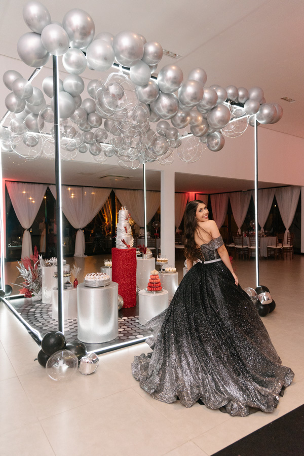Cenário de luxo no Espaço JK Jacareí! A debutante posa elegante em seu vestido em frente a Mesa do bolo. Uma produção visual impactante para uma festa de 15 anos perfeita.