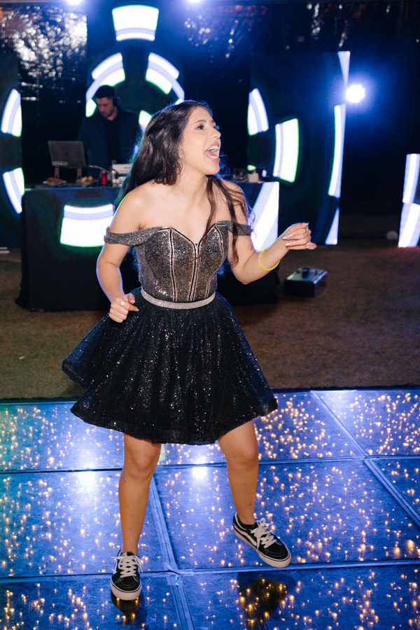 Brilhando na pista do Espaço JK Jacareí! A debutante se solta e dança com alegria, com seu vestido preto de paetês refletindo as luzes desta balada inesquecível de 15 anos.