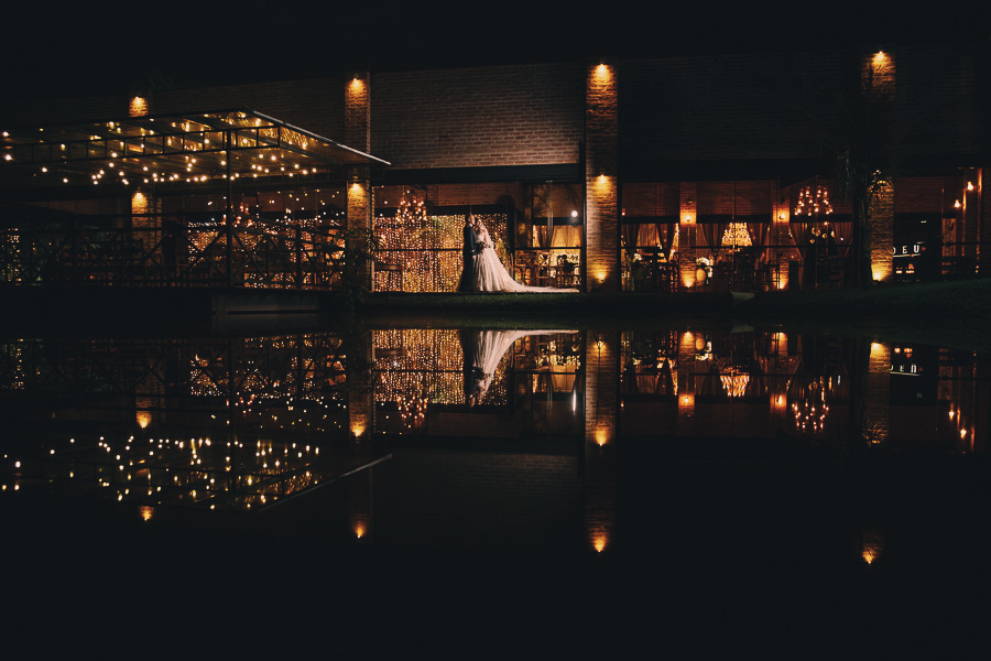 Casamento noturno no Amadeus Buffet Crystal em Taubaté com iluminação cênica e reflexo dos noivos na água