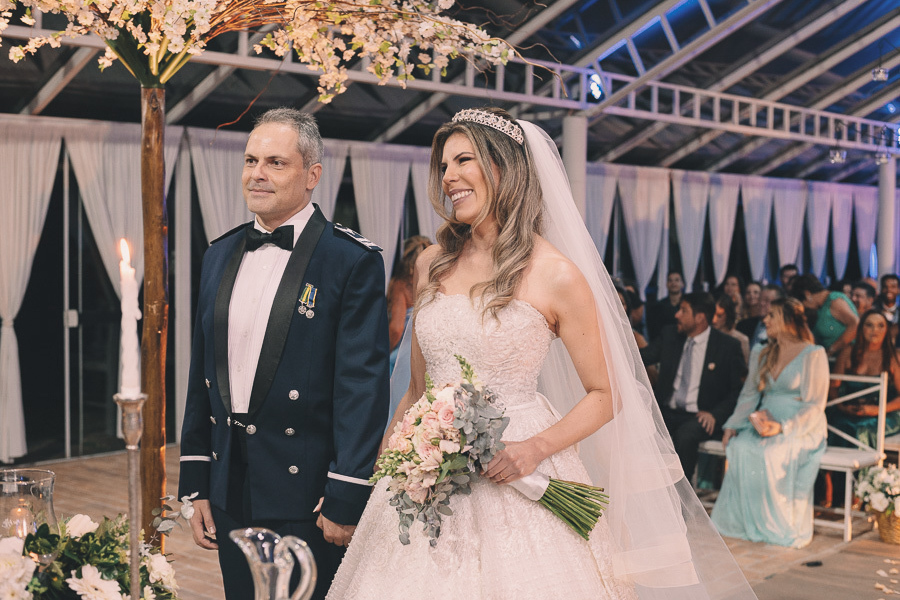 Casamento militar em Taubaté: noivos no altar da Capela de Cristal do Amadeus Buffet com decoração romântica