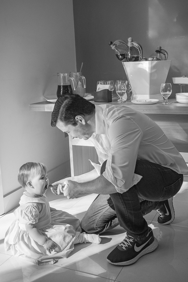 A conexão entre pai e filha em um registro atemporal. A fotografia documental de aniversário infantil busca esses instantes de pura interação e carinho.