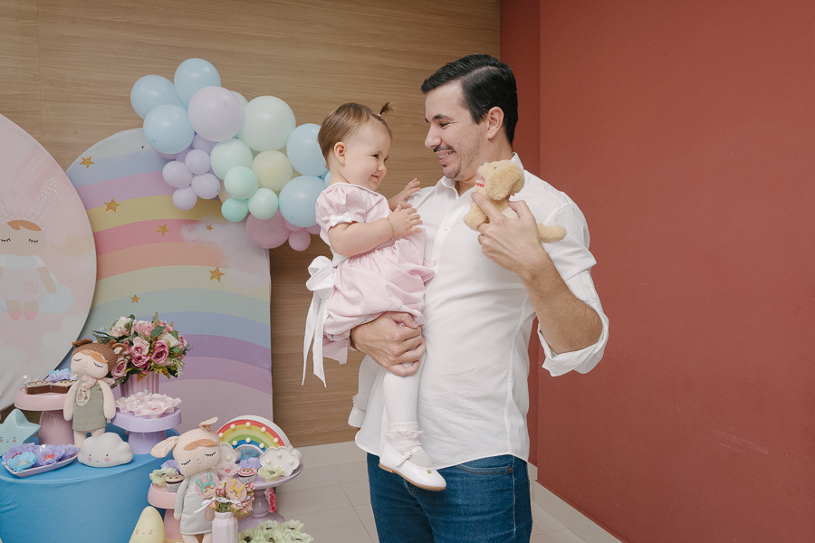 Voando alto no colo do papai! Um clique que transmite a alegria, a confiança e a energia contagiante de um aniversário infantil.